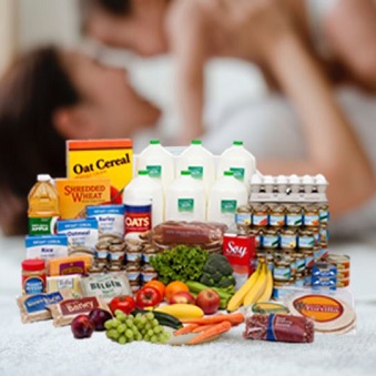 Groceries, fruits, and vegetables in foreground, Woman with Infant in Background. 